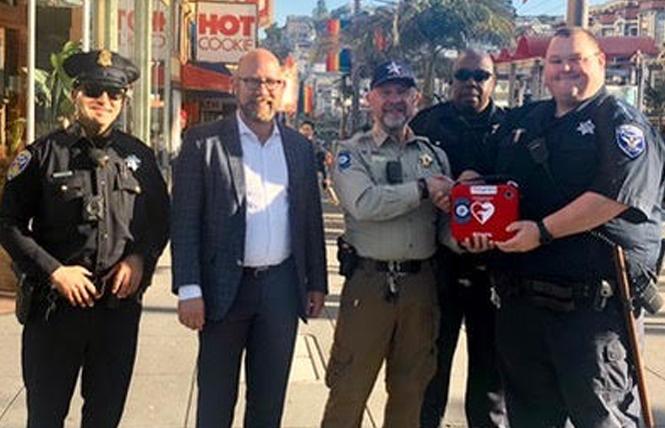 Greg Carey, center, chief of patrol for Castro Community on Patrol, recently handed over an automatic external defibrillator to San Francisco Patrol Special Police Officers TJ Jones and Cody Clements, right. Supervisor Rafael Mandelman, second from left, was joined by a San Francisco police beat officer at the brief ceremony. Photo: Courtesy Greg Carey