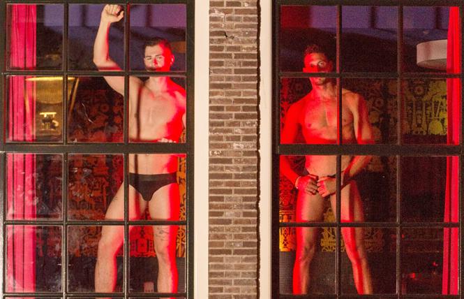 Escort model Lukas Daken, left, dances with a fellow HUNQZ escort model, right, to raise awareness of sex worker's labor rights in the My Red Light window in Amsterdam's red-light district during Amsterdam Pride August 3. Photo: www.keefwilliams.com