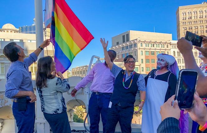 Oakland Mayor Libby Schaaf, second from left, raises the Pride flag at Oakland City Hall Tuesday as out Councilwoman Rebecca Kaplan raises her hand. Photo: Jane Philomen Cleland