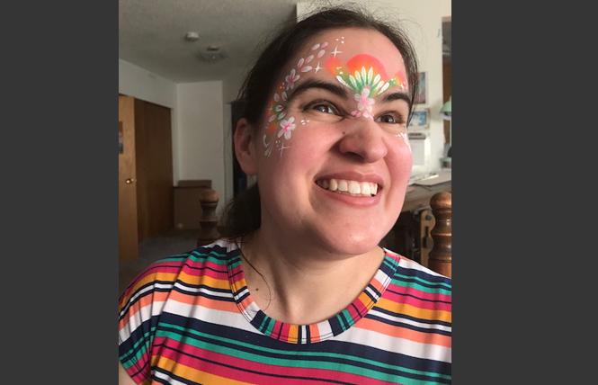 Caitlin Hernandez is beaming as she wears rainbow face paint with stars, dots, and flower petals. Photo: Jack Sanders/Face paint: Haley Brown, www.haleybrown.org.