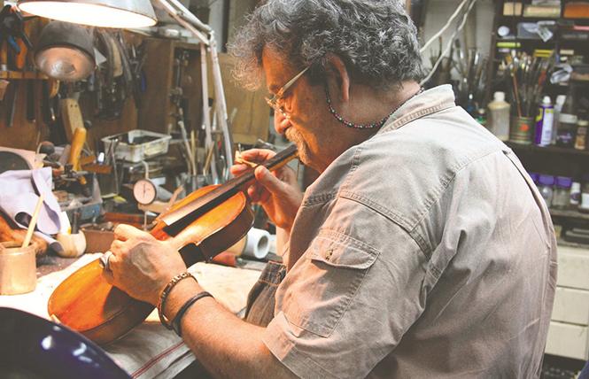 Luthier Amnon Weinstein working on restoring a Violin of Hope in his workshop. Photo: Courtesy Amnon Weinstein