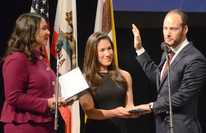 Mayor London Breed, left, administers the oath of office January 8 to District Attorney Chesa Boudin, who was joined on stage by his wife, Valerie Block. Photo: Rick Gerharter