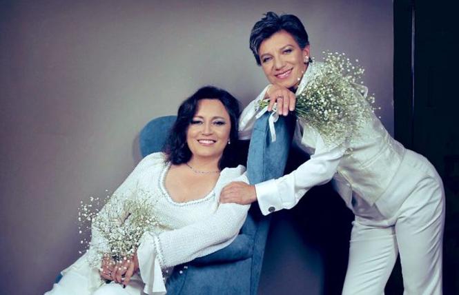 Angel Yanez, sitting in a chair, posed with her wife, Bogota Mayor Claudia López, in a wedding photo the couple released. Photo Credit: Raúl Higuera/Claudia López/Twitter