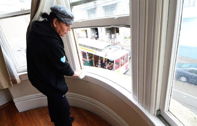 Jane Cordova cleans the windowsill in her new room at the Trans Home SF apartment, which overlooks the cable car route. Photo: Rick Gerharter