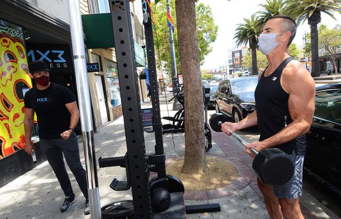 MX3 Fitness co-owner Glenn Shope, left, directs Shayne Jones through his outdoor workout on the Market Street sidewalk outside the business due to COVID-19 restrictions. Photo: Rick Gerharter