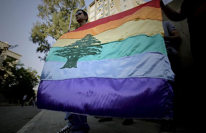 A Pride flag bearing the cedar tree in the middle of it is carried by a human rights activist during an anti-homophobia rally in Beirut. Photo: Courtesy of Joseph EID/AFP