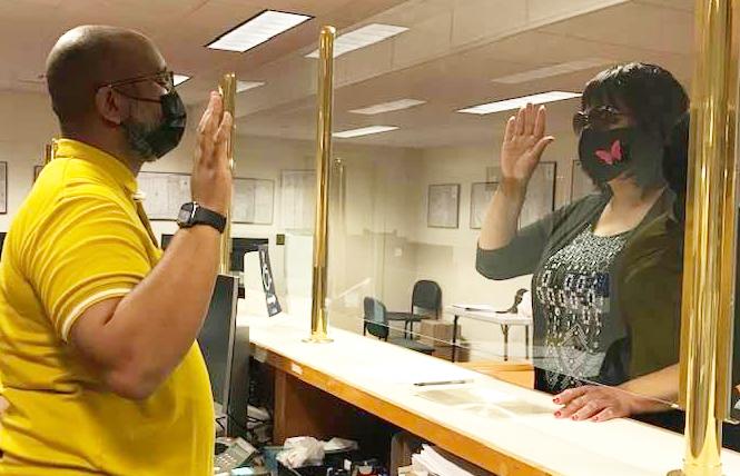 Ms. Billie Cooper, right, raises her hand after filling out paperwork at the elections department to run for District 6 supervisor. Photo: Courtesy Ms. Billie Cooper