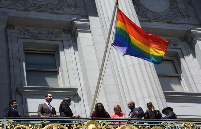 Officials stood on the Mayor's Balcony and raised the rainbow flag to celebrate the beginning of LGBTQ Pride Month and the reopening of City Hall. Photo: Rick Gerharter
