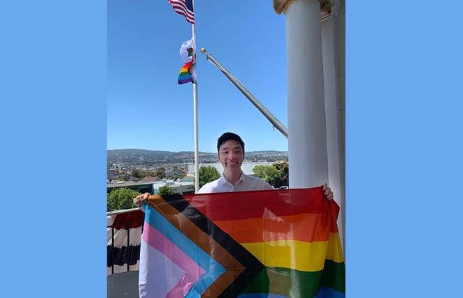 James Coleman, South San Francisco's first LGBTQ city councilman, holds the Progress Pride flag outside City Hall. Photo: Courtesy James Coleman
