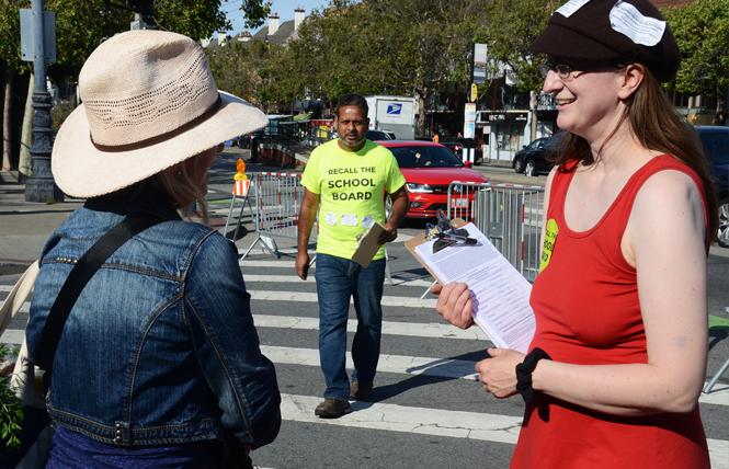 Autumn Looijen, right, asked Angela Rossoff to sign a petition to recall three members of the San Francisco School Board at the Castro Farmers Market in June. Her partner, Siva Raj, center, also was collecting signatures. Photo: Rick Gerharter