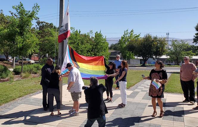 Helping to raise the Progress Pride flag with gay Morgan Hill City Councilmember René Spring, in white shirt, were Morgan Hill Mayor Rich Constantine, left at flagpole, and Melissa De La Cruz, in cap. Photo: Courtesy Kevin Rodriguez Cristobal 