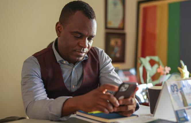 Frank Mugisha, executive director of Sexual Minorities Uganda, checks his phone in his office in Kampala. Photo: Courtesy Civil Rights Defenders