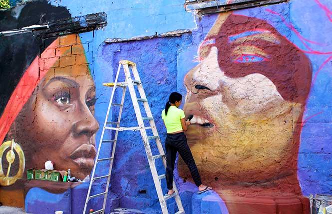 A woman paints a mural in Cartagena's historic walled city in Colombia. Photo: Heather Cassell