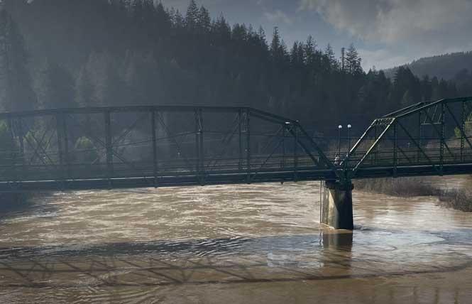 A swollen Russian River, seen Monday, January 9, from Highway 116 toward the walking bridge and Johnson's beach in Guerneville. Photo: George Pedroni