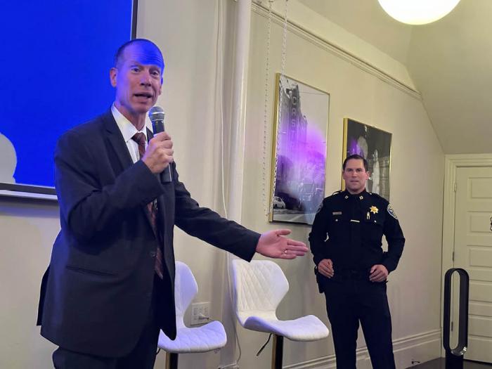 Robert Tripp, left, special agent in charge at the FBI's San Francisco office, was obscured in blue light as he spoke about the bureau's commitment to enforcing federal hate crime laws at The Academy events venue in the Castro August 30. San Francisco Police Department Captain Christopher Del Gandio, who is the first out person to become a captain in the department, looked on. Photo: John Ferrannini
