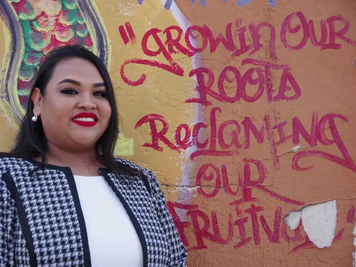 Oakland school board candidate Sasha Ritzie-Hernandez stands in front of the mural "Reclaiming Fruitvale." Photo: Courtesy the campaign