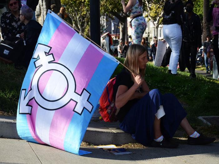 A person sits with a transgender flag at this year's Trans March. The group Protect Kids California's three anti-trans California ballot measures have been cleared for signature gathering by the secretary of state's office. Photo: Rick Gerharter