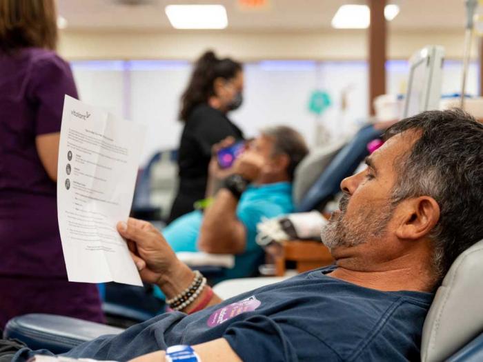 A person reads an information sheet while donating blood at Vitalant. Photo: Courtesy Vitalant