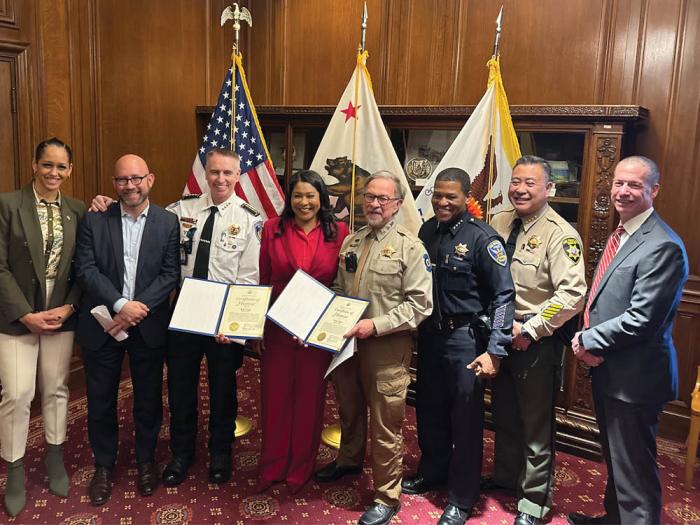 San Francisco District Attorney Brooke Jenkins, left, joined District 8 Supervisor Rafael Mandelman, Ken Craig of Castro Community on Patrol, Mayor London Breed, Greg Carey of Castro Community on Patrol, Police Chief William Scott, Sheriff Paul M. Miyamoto and San Francisco FBI Special Agent in Charge Robert Tripp as the mayor and Tripp presented the CCOP leaders with certificates of appreciation March 18 at City Hall. Craig and Carey will receive the FBI Community Leadership Award from Director Christopher Wray next month in Washington, D.C. Photo: John Ferrannini